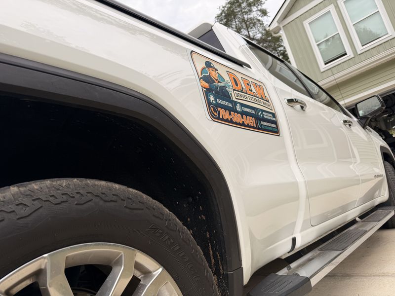 White Denver Exterior Wash pickup truck with the D.E.W. logo magnet on the door, parked in a driveway