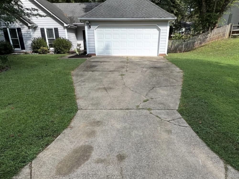 Before: concrete driveway with dark oil stains and grime, seen from the street
